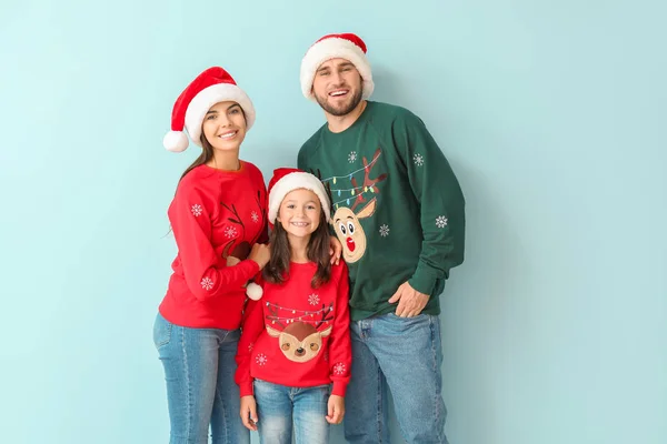 Happy family in Christmas sweaters and Santa hats on color background — Stock Photo, Image