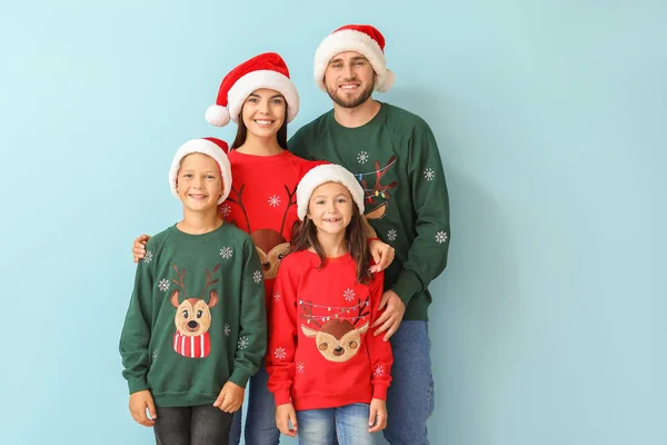 Щаслива сім'я в різдвяних светрах і капелюхах на кольоровому фоні — стокове фото