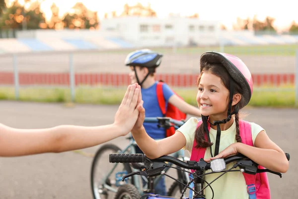 Cute children giving each other high-five while riding bicycles outdoors — Stock Photo, Image