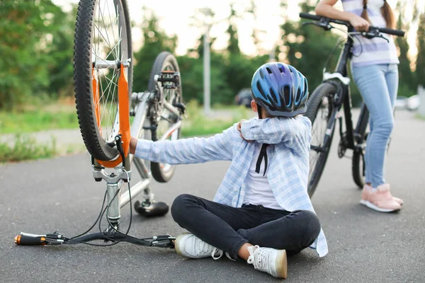 Niño triste sentado cerca de la bicicleta dañada al aire libre — Foto de Stock