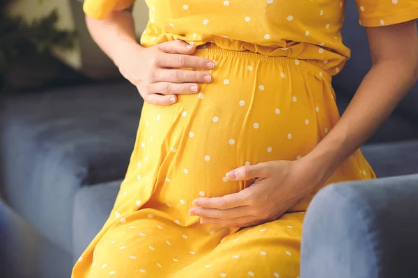 Mooie zwangere vrouw zittend op de bank, close up — Stockfoto