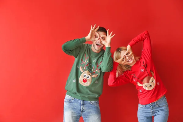 Funny couple in Christmas sweaters on color background — Stock Photo, Image