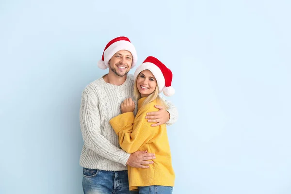 Pareja feliz en los sombreros de Santa sobre fondo de color — Foto de Stock