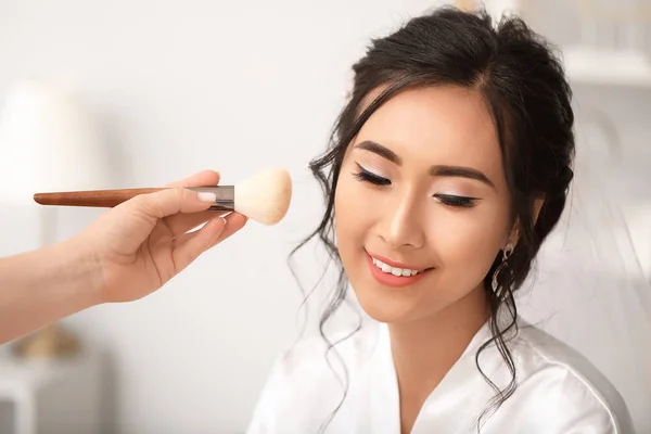 Profesjonalny makijaż artysta pracujący z młodą azjatycką narzeczoną w domu — Zdjęcie stockowe
