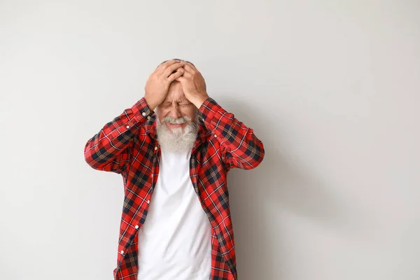 Старший мужчина страдает от головной боли на светлом фоне — стоковое фото