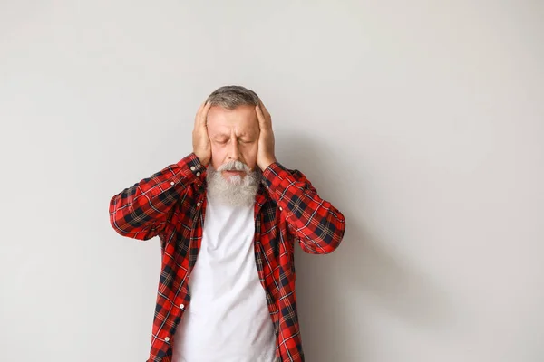 Senior man die last heeft van hoofdpijn op lichte achtergrond — Stockfoto