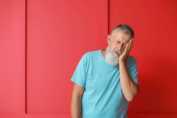 Senior man suffering from headache on color background — Stock Photo, Image