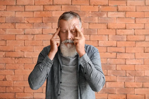 Kıdemli adam tuğla duvardan dolayı baş ağrısı çekiyor.