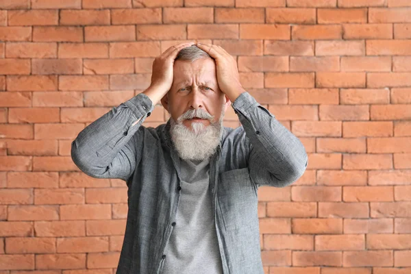 Kıdemli adam tuğla duvardan dolayı baş ağrısı çekiyor.