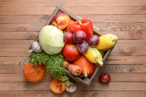 Коробка со многими полезными овощами и фруктами на деревянном фоне — стоковое фото