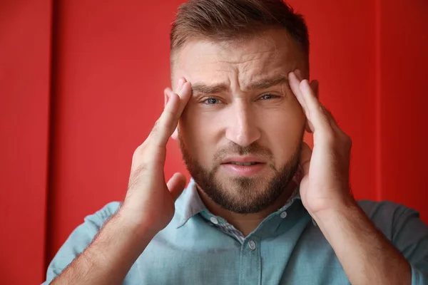 Young man suffering from headache on color background — Stock Photo, Image