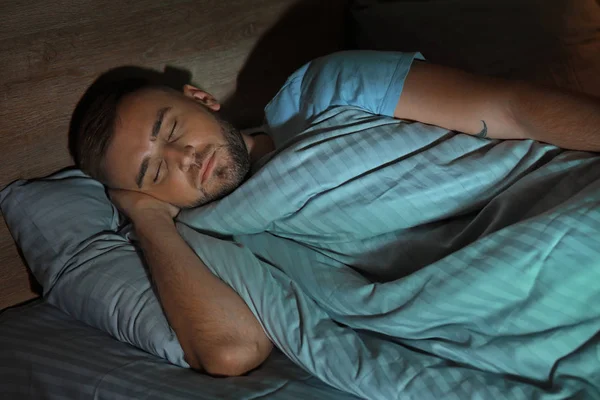 Joven durmiendo en la cama por la noche — Foto de Stock