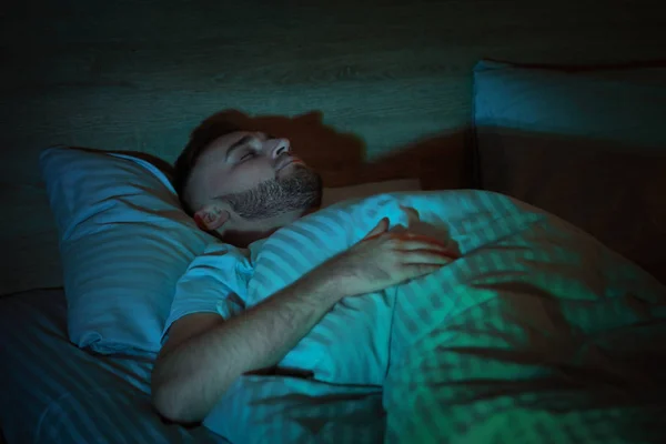 Jovem dormindo na cama à noite — Fotografia de Stock