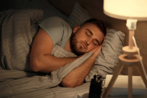 Mladý muž spí v noci v posteli — Stock fotografie