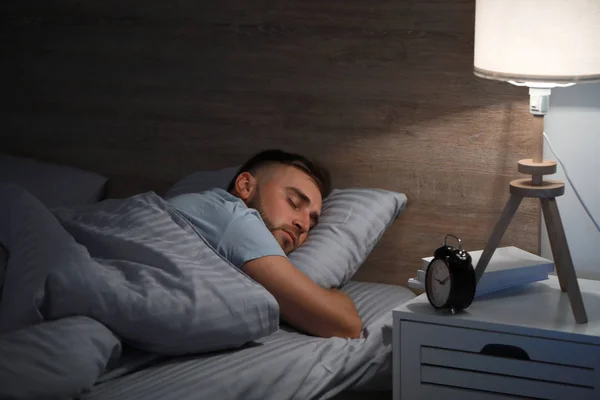 Jovem dormindo na cama à noite — Fotografia de Stock