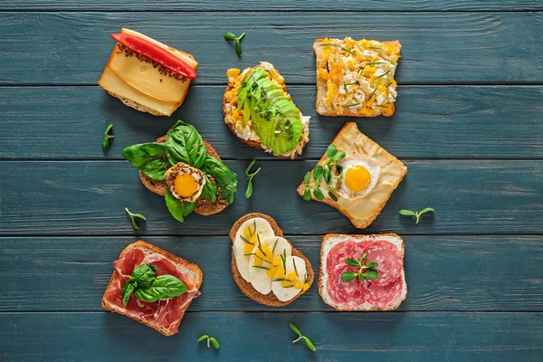 Different tasty sandwiches on wooden table — Stock Photo, Image