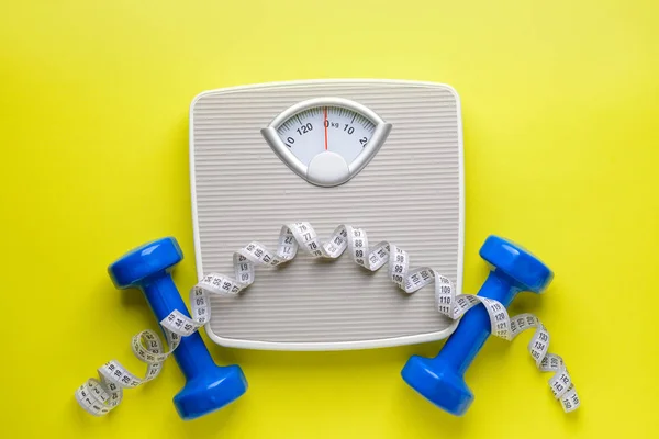 Scales, dumbbells and measuring tape on color background. Weight loss concept — 스톡 사진