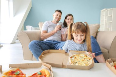 Mutlu aile evde pizza yiyor.