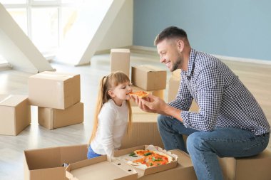 Mutlu baba ve küçük kızı taşınma gününde pizza yiyorlar.