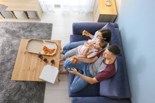 Familia feliz comiendo pizza mientras ve la televisión en casa —  Fotos de Stock