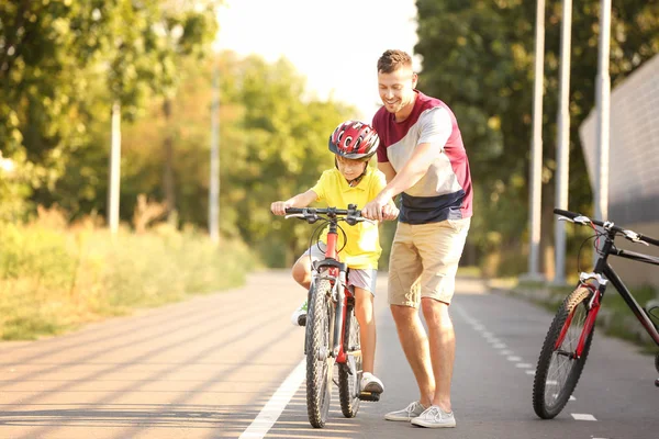 Padre enseñando a su hijo a andar en bicicleta al aire libre — Foto de Stock