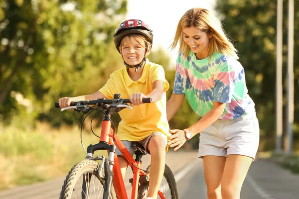 Mãe ensinando seu filho a andar de bicicleta ao ar livre — Fotografia de Stock