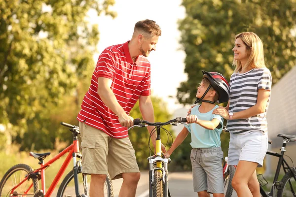 Parents teaching their son to ride bicycle outdoors