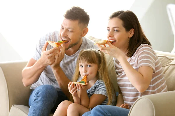 Happy family eating pizza while watching TV at home Royalty Free Stock Images