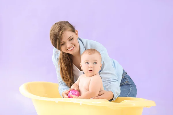 Ibu memandikan bayinya yang lucu dengan latar belakang warna — Stok Foto