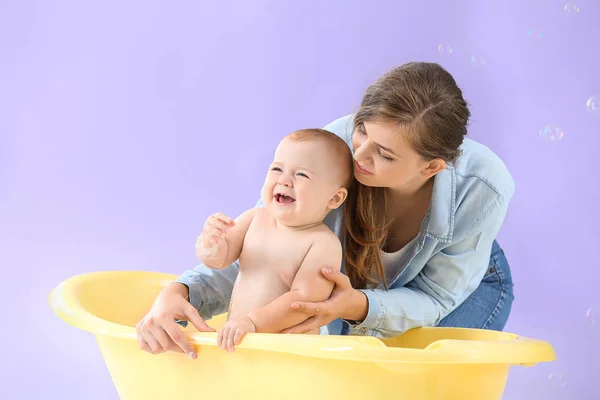 Ibu memandikan bayinya yang lucu dengan latar belakang warna — Stok Foto