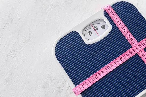 Scales and measuring tape on light background. Weight loss concept — Stock Photo, Image