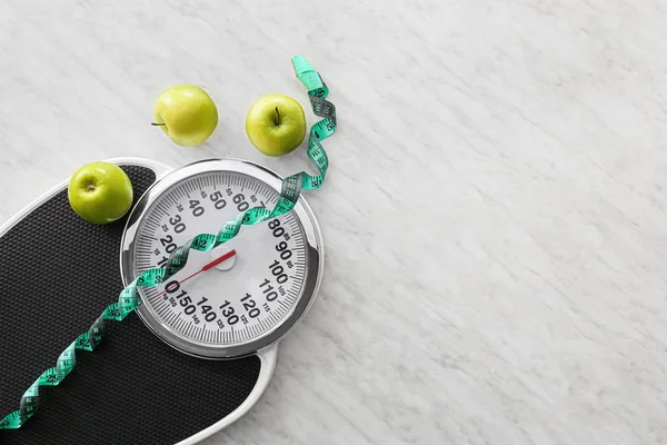 Scales, apples and measuring tape on light background. Weight loss concept — 스톡 사진