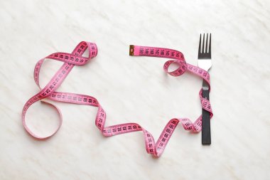 Işık arka planında mezurası olan çatal. Diyet kavramı