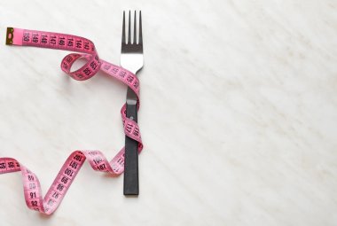 Işık arka planında mezurası olan çatal. Diyet kavramı