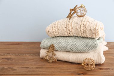 Ahşap masanın üzerinde Noel süsü olan kışlık giysiler yığını.