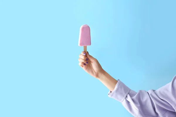 配色背景的蓝莓冰淇淋的雌性手 — 图库照片