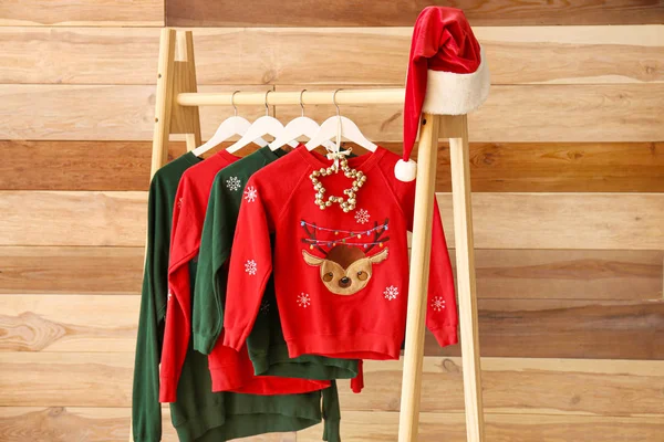 Rack with Christmas clothes on wooden background — Stock Photo, Image