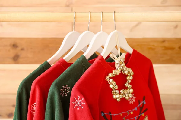 Rack with Christmas clothes on wooden background — Stock Photo, Image