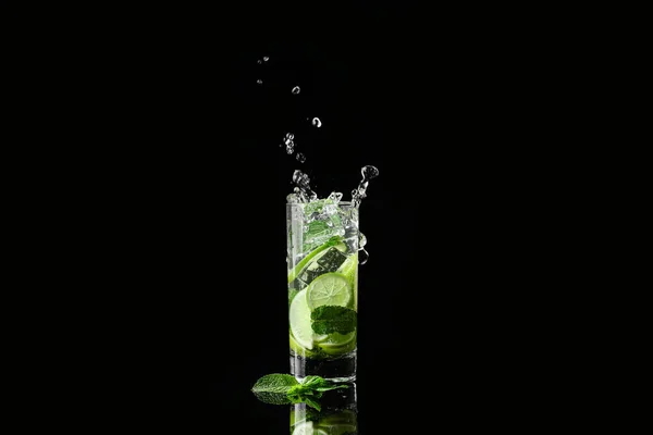 Glass of fresh mojito with splashes on dark background — Stock Photo, Image