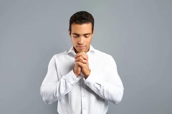 Young African-American man praying on grey background — Stock Photo, Image