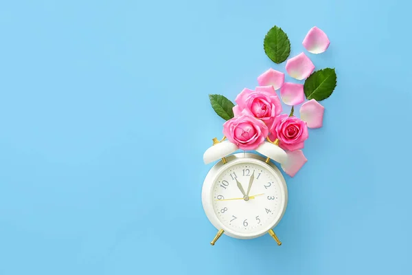 Beautiful rose flowers with alarm clock on color background — Stock Photo, Image