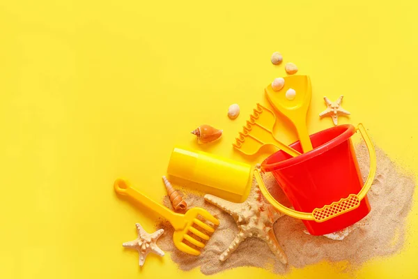 Juguetes de playa para niños con arena sobre fondo de color —  Fotos de Stock