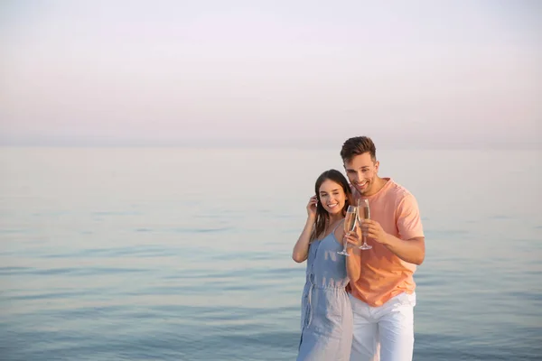 Jeune couple buvant du champagne sur la plage — Photo