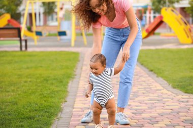 Afro-Amerikalı anne açık havada yürümeyi küçük bebeğine öğretiyor