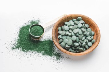 Sarmaşık hapları ve beyaz arka planda pudra dolu bir kase.