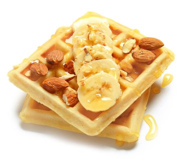 Beyaz zemin üzerinde muz, bal ve badem olan lezzetli waffle 'lar.