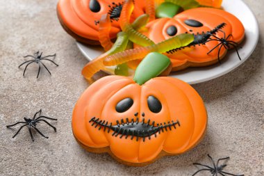 Gri arka planda Cadılar Bayramı kutlaması için yaratıcı kurabiyelerle dolu tabak.