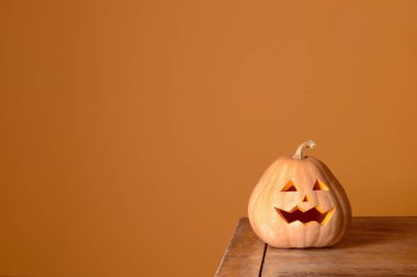 Ahşap masadaki Cadılar Bayramı kabağı renk arkaplanına karşı