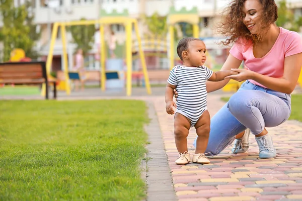 Afro-Amerikalı anne açık havada yürümeyi küçük bebeğine öğretiyor