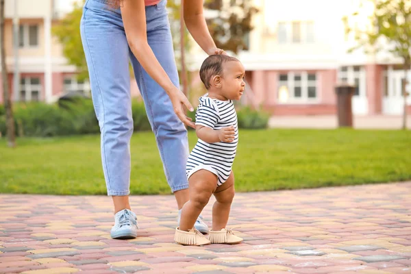African-American mother teaching her little baby to walk outdoors — Stock Photo, Image